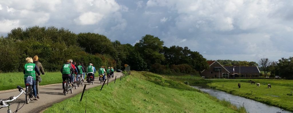 Een mooie sliert tandems door een Hollands dijk landschap